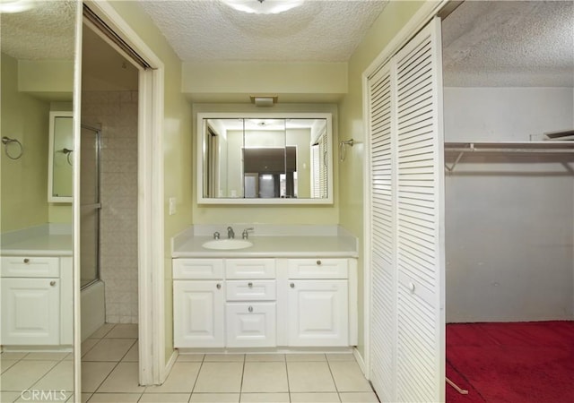 bathroom with vanity, shower / bath combination with glass door, tile patterned flooring, and a textured ceiling