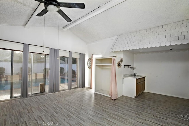 interior space featuring ceiling fan, lofted ceiling with beams, sink, and a textured ceiling