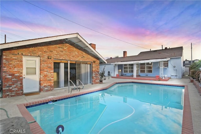 pool at dusk featuring a patio