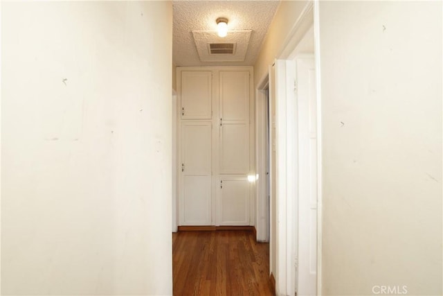 corridor with dark hardwood / wood-style flooring and a textured ceiling