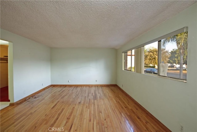 spare room featuring light hardwood / wood-style floors and a textured ceiling