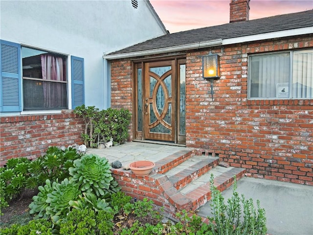 exterior entry at dusk featuring a patio