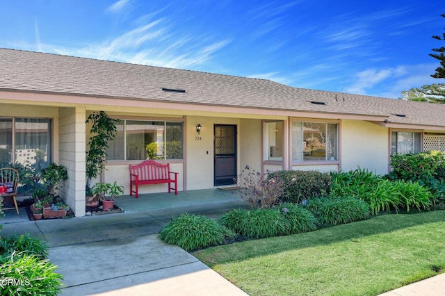 doorway to property featuring covered porch and a lawn