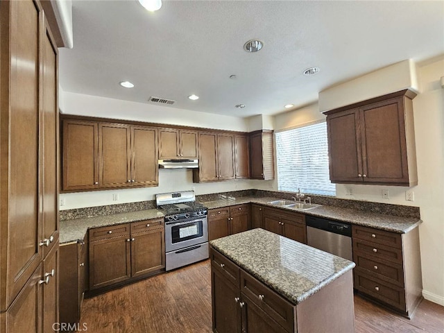 kitchen featuring sink, appliances with stainless steel finishes, a kitchen island, dark hardwood / wood-style floors, and stone countertops