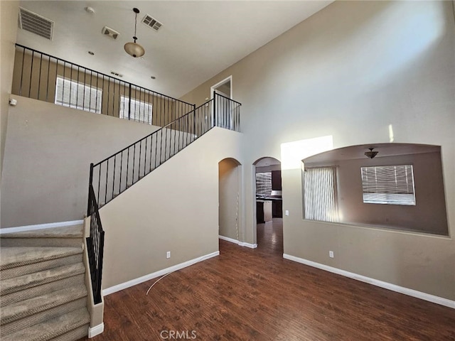 stairs featuring a towering ceiling and wood-type flooring