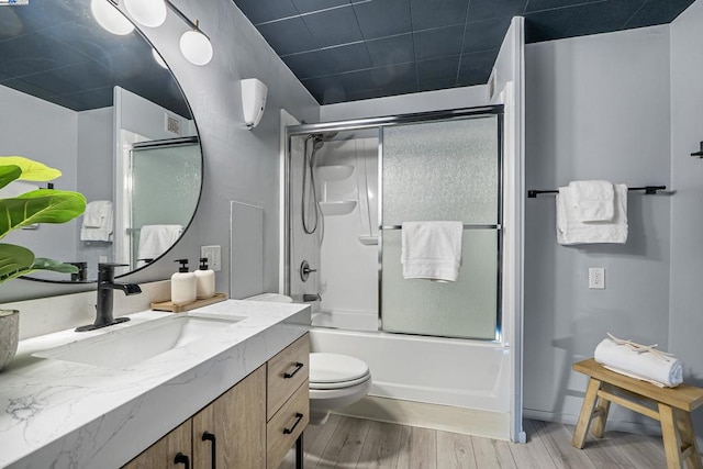 full bathroom with toilet, vanity, combined bath / shower with glass door, and hardwood / wood-style floors