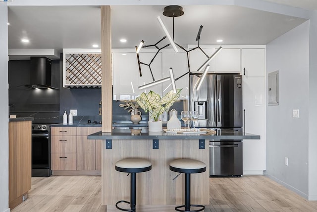 kitchen featuring stainless steel fridge with ice dispenser, black range with electric stovetop, light hardwood / wood-style floors, and wall chimney exhaust hood