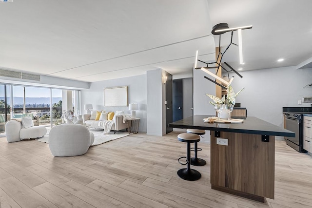 kitchen featuring a kitchen island, a breakfast bar, electric range, and light hardwood / wood-style floors