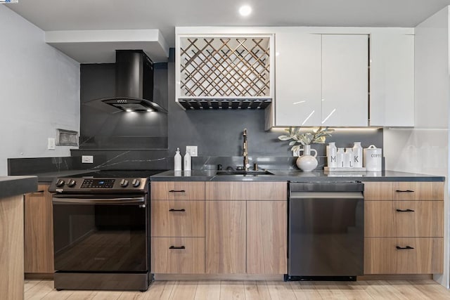 kitchen featuring sink, white cabinets, light hardwood / wood-style floors, stainless steel appliances, and wall chimney range hood