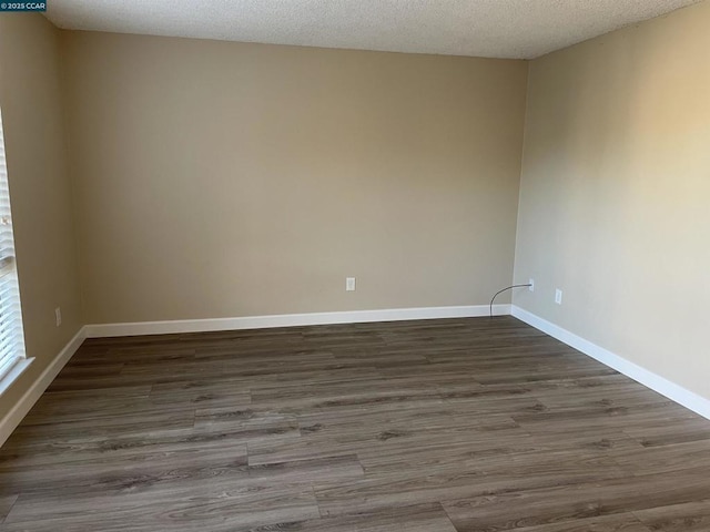 unfurnished room with dark wood-type flooring and a textured ceiling