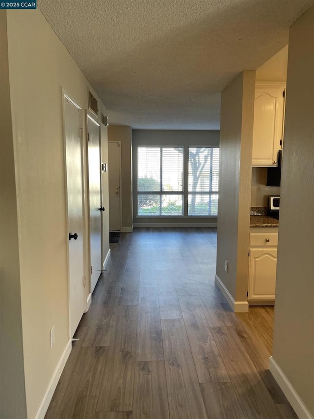 hallway with dark hardwood / wood-style flooring and a textured ceiling