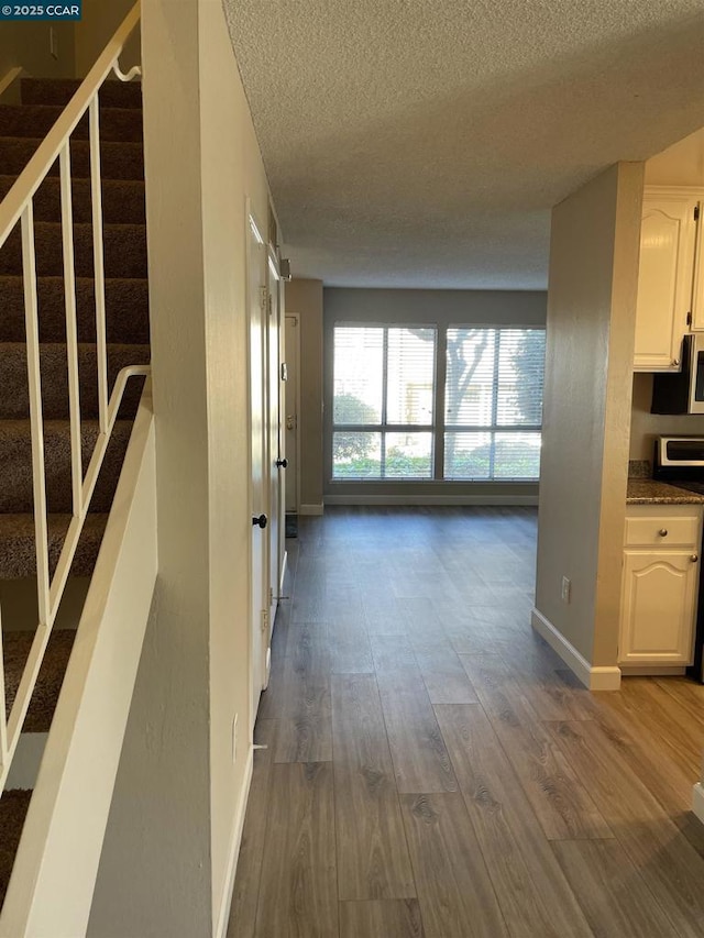 corridor with dark hardwood / wood-style floors and a textured ceiling