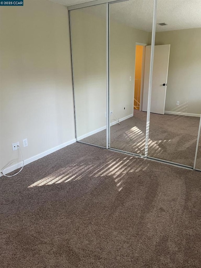 unfurnished bedroom with a textured ceiling and carpet flooring