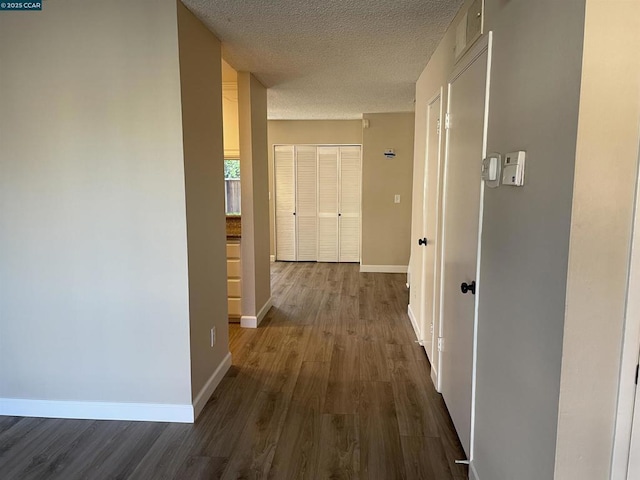 hall with dark wood-type flooring and a textured ceiling