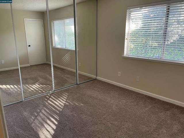 unfurnished bedroom with multiple windows, carpet floors, and a closet