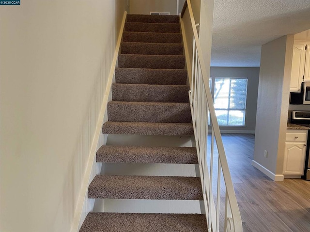 stairs featuring hardwood / wood-style flooring and a textured ceiling