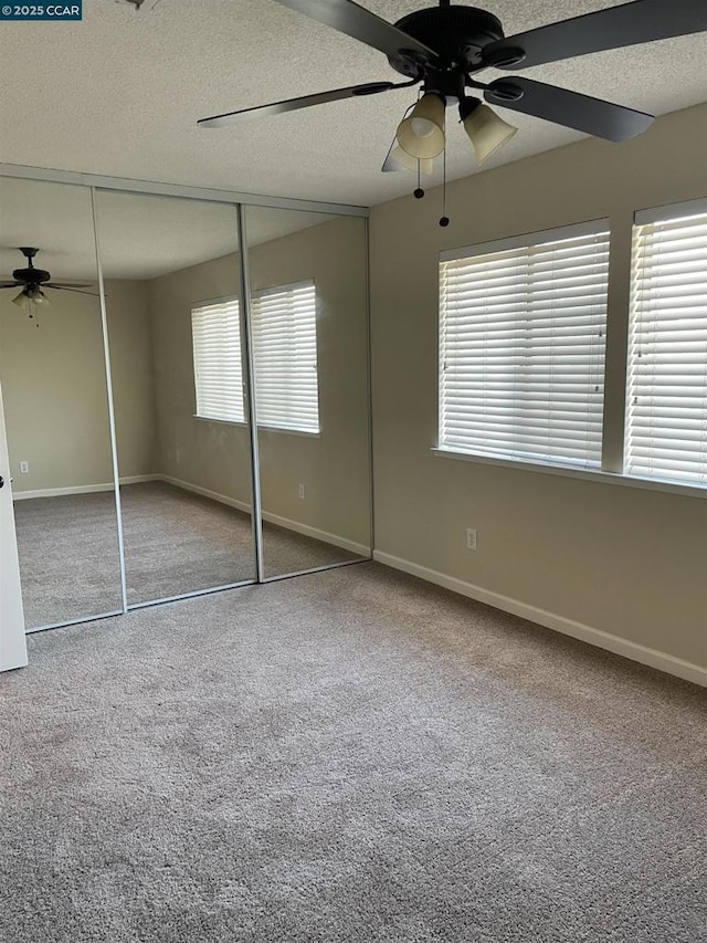 unfurnished bedroom with ceiling fan, carpet flooring, a closet, and a textured ceiling