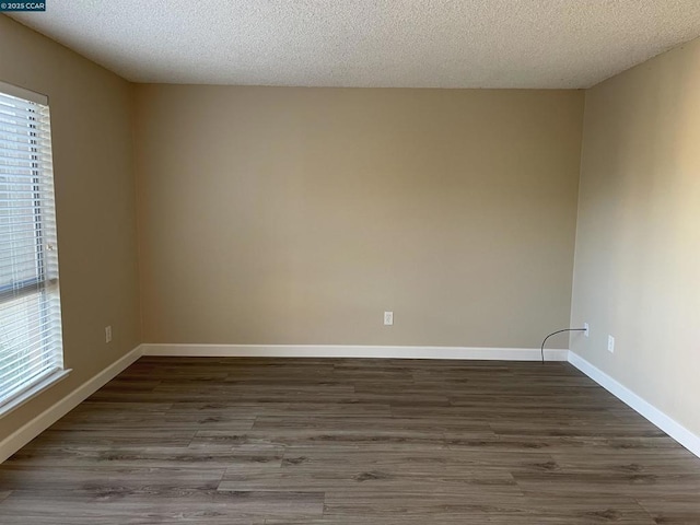 unfurnished room featuring dark hardwood / wood-style floors and a textured ceiling