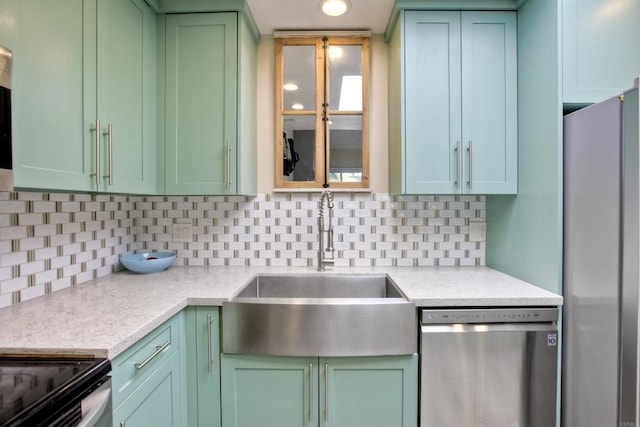 kitchen featuring sink, tasteful backsplash, light stone counters, green cabinets, and stainless steel appliances