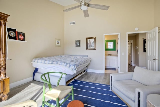 bedroom featuring sink, ensuite bath, hardwood / wood-style flooring, ceiling fan, and a towering ceiling