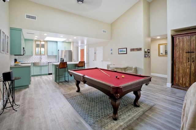 game room featuring billiards, light hardwood / wood-style floors, and high vaulted ceiling