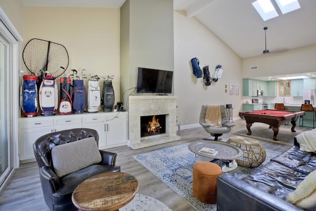 interior space with a fireplace, a skylight, billiards, light wood-type flooring, and beam ceiling