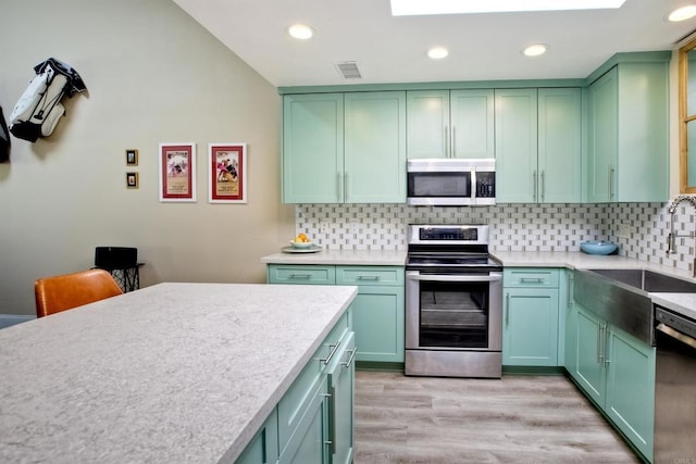 kitchen featuring sink, green cabinets, backsplash, and appliances with stainless steel finishes