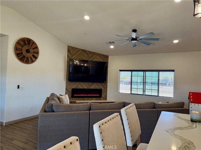 living room with wood-type flooring, ceiling fan, and a large fireplace