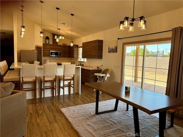 dining area featuring vaulted ceiling, an inviting chandelier, and hardwood / wood-style floors