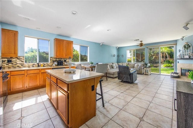 kitchen featuring a kitchen island, a breakfast bar area, decorative backsplash, light tile patterned floors, and a high end fireplace