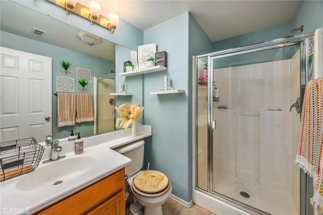 bathroom with tile patterned flooring, vanity, a shower with door, and toilet