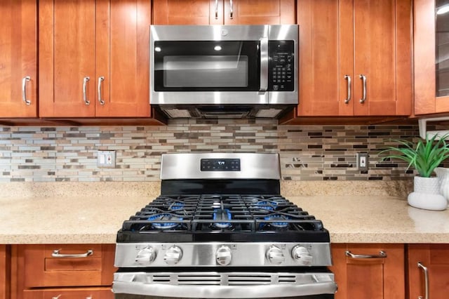 kitchen with stainless steel appliances, light stone countertops, and backsplash