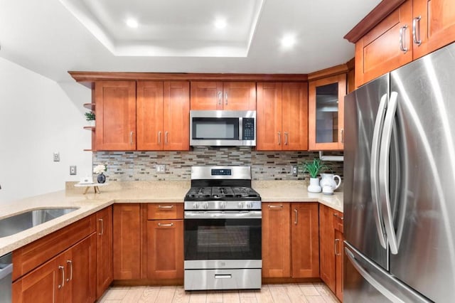 kitchen with light stone counters, backsplash, sink, and appliances with stainless steel finishes