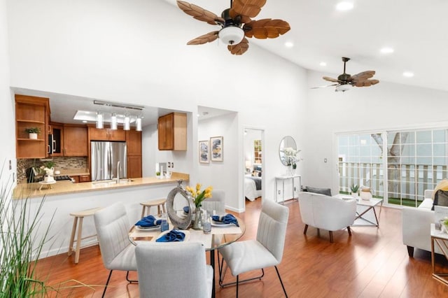 dining area featuring light hardwood / wood-style flooring, high vaulted ceiling, and ceiling fan