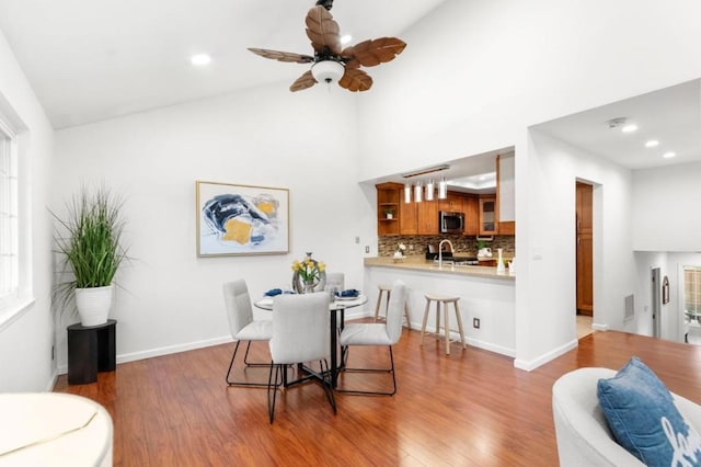 dining room featuring hardwood / wood-style floors, high vaulted ceiling, and ceiling fan