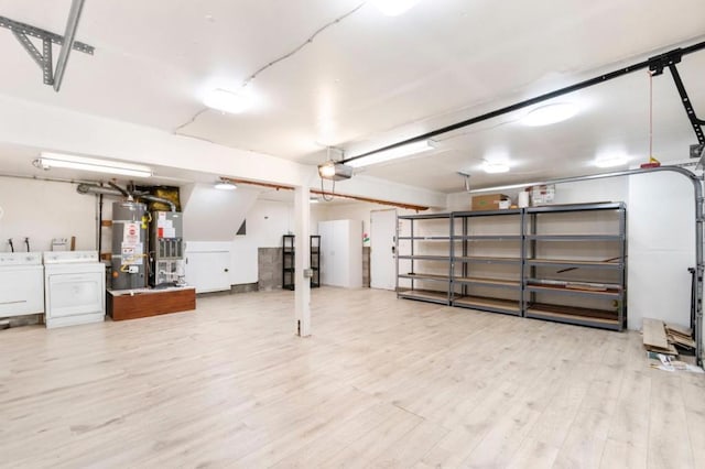 basement featuring separate washer and dryer, light wood-type flooring, and strapped water heater