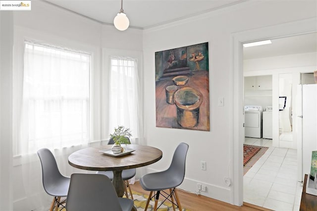 dining space featuring washing machine and clothes dryer, ornamental molding, tile patterned flooring, and a wealth of natural light