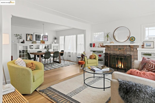 living room featuring a tiled fireplace, hardwood / wood-style floors, and a healthy amount of sunlight