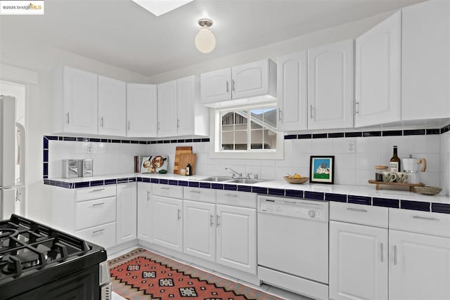 kitchen featuring white cabinetry, tile countertops, white dishwasher, and decorative backsplash