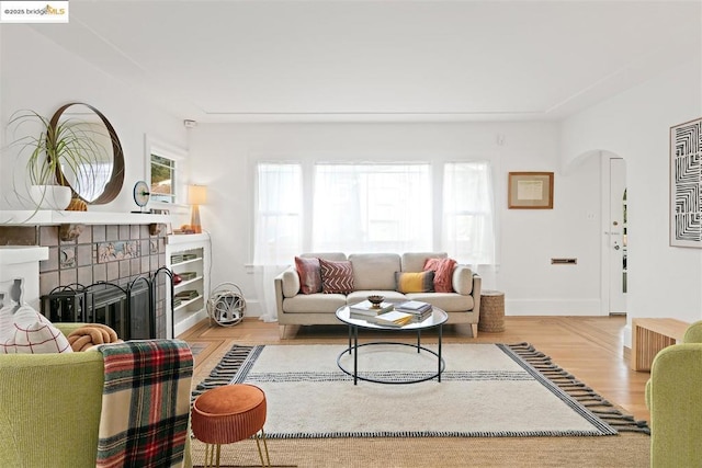 living room with a tiled fireplace and light wood-type flooring