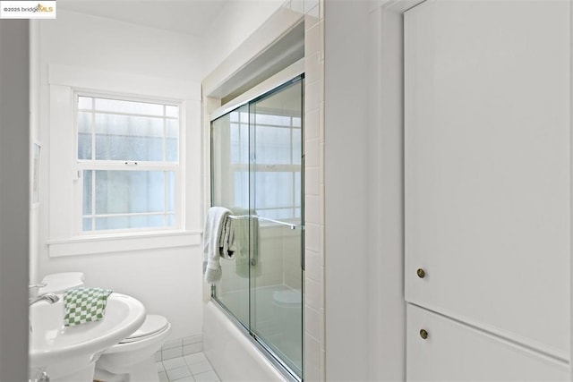 bathroom featuring enclosed tub / shower combo, a healthy amount of sunlight, toilet, and tile patterned flooring