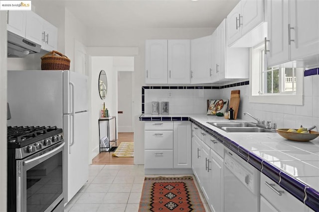 kitchen featuring white cabinetry, tile counters, and stainless steel gas range