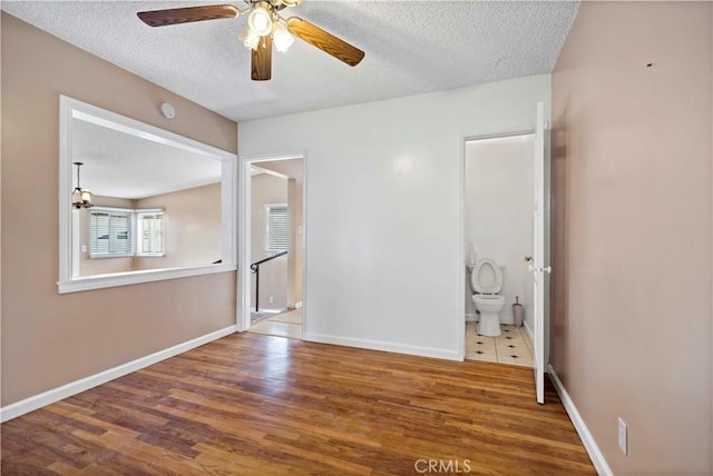 unfurnished room with hardwood / wood-style flooring, ceiling fan, and a textured ceiling