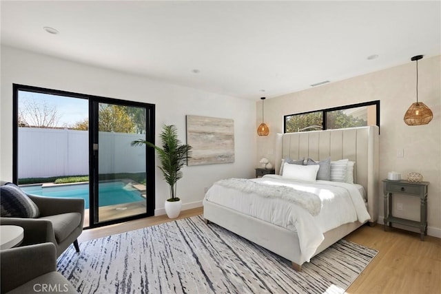 bedroom featuring multiple windows, access to exterior, and light hardwood / wood-style floors