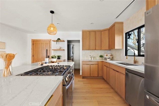 kitchen featuring sink, light hardwood / wood-style flooring, appliances with stainless steel finishes, light brown cabinetry, and decorative light fixtures