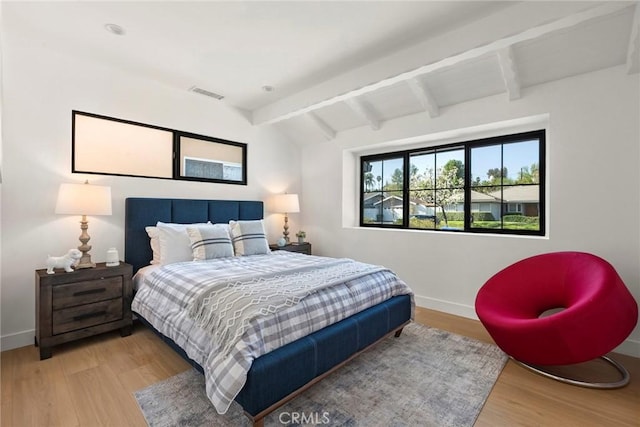 bedroom with lofted ceiling with beams and wood-type flooring