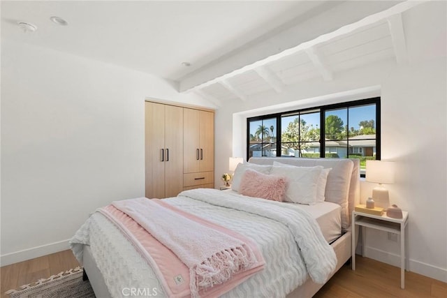 bedroom featuring vaulted ceiling with beams, hardwood / wood-style floors, and a closet