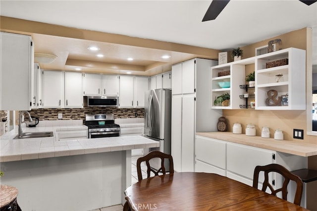 kitchen featuring white cabinetry, a kitchen bar, kitchen peninsula, and appliances with stainless steel finishes