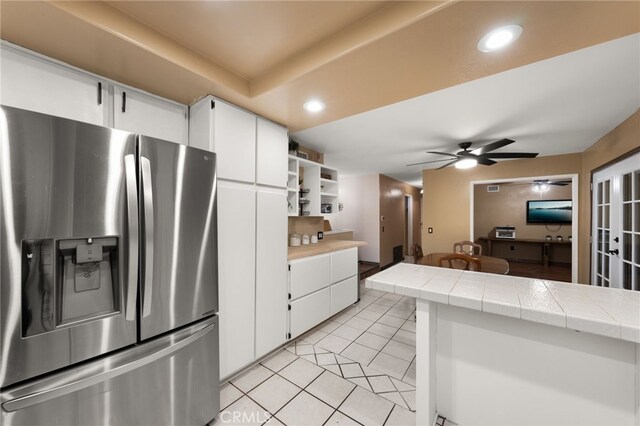 kitchen with light tile patterned flooring, white cabinetry, tile counters, ceiling fan, and stainless steel refrigerator with ice dispenser