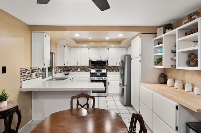 kitchen with white cabinetry, sink, stainless steel appliances, and kitchen peninsula